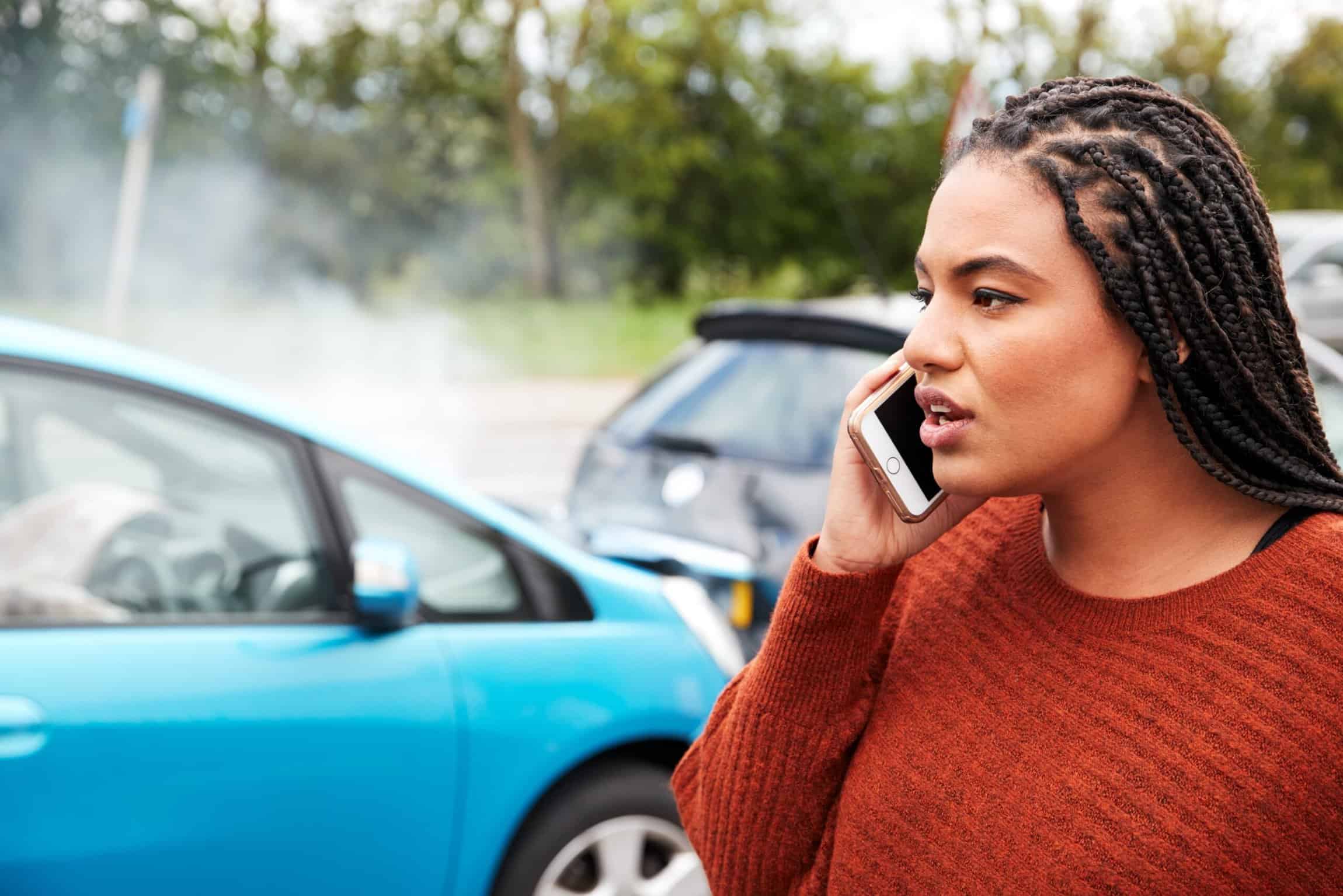 Woman on the phone in front of an out of focus T-Bone Collision Car Accident. Steps to Take After T-Bone Collision Concept