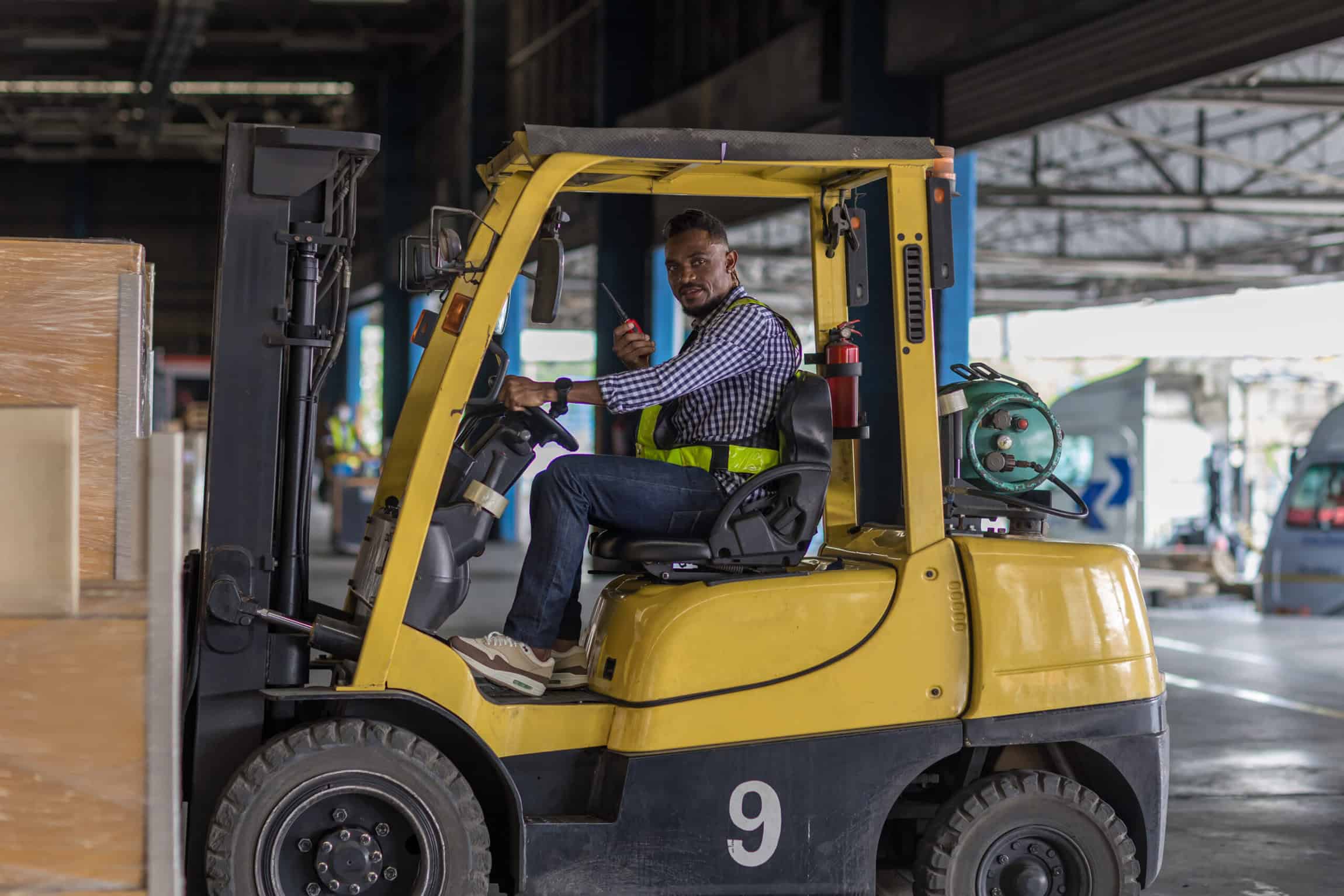 Man worker at forklift driver happy working in industry factory logistic ship. Man forklift driver in warehouse area. Forklift driver sitting in vehicle in warehouse