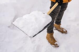 Man cleaning snow from sidewalk and using snow shovel. When Do Virginia Premises Liability Cases Usually Occur concept