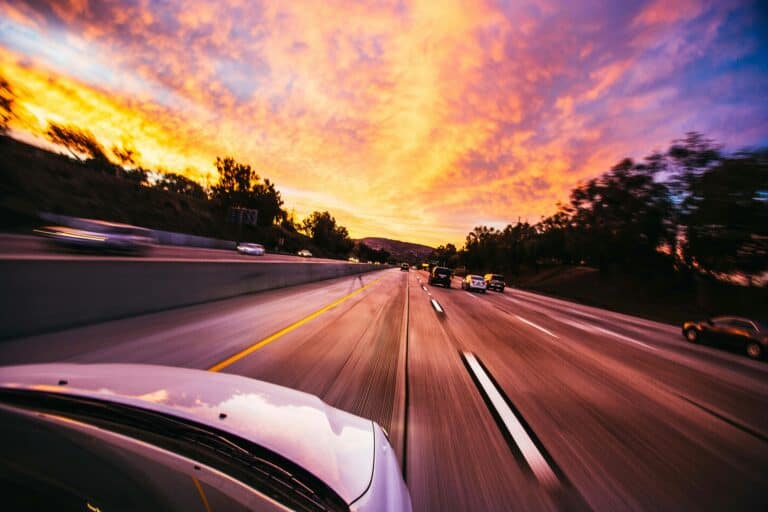 Car going fast on highway during sunset - auto accident lawyer concept.